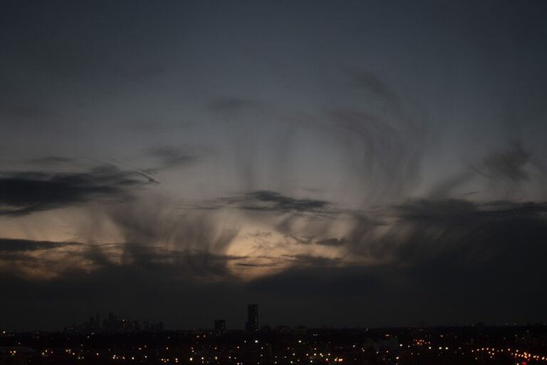 the sky in three different colours. light blue, dark blue, and peach. the clouds are in different shapes.