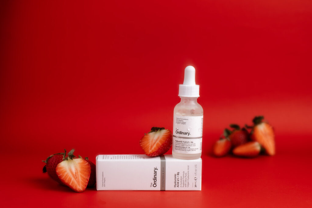 the ordinary hyaluronic acid product on a red background. surrounded by strawberries