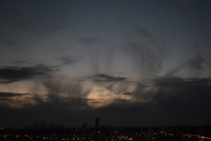 the sky in three different colours. light blue, dark blue, and peach. the clouds are in different shapes.